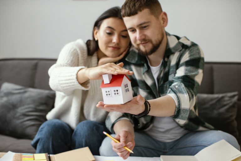 Pareja joven sosteniendo una maqueta de casa, planificando la compra de su primera vivienda con subsidio.