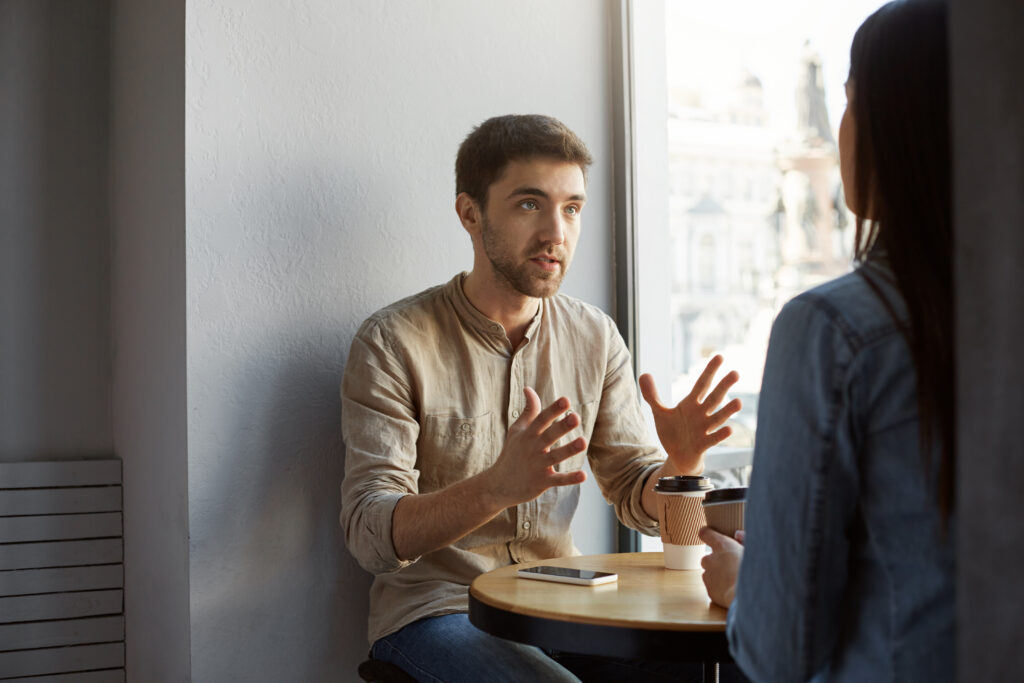 Hombre joven advirtiendo sobre fraudes durante una conversación seria en una cafetería