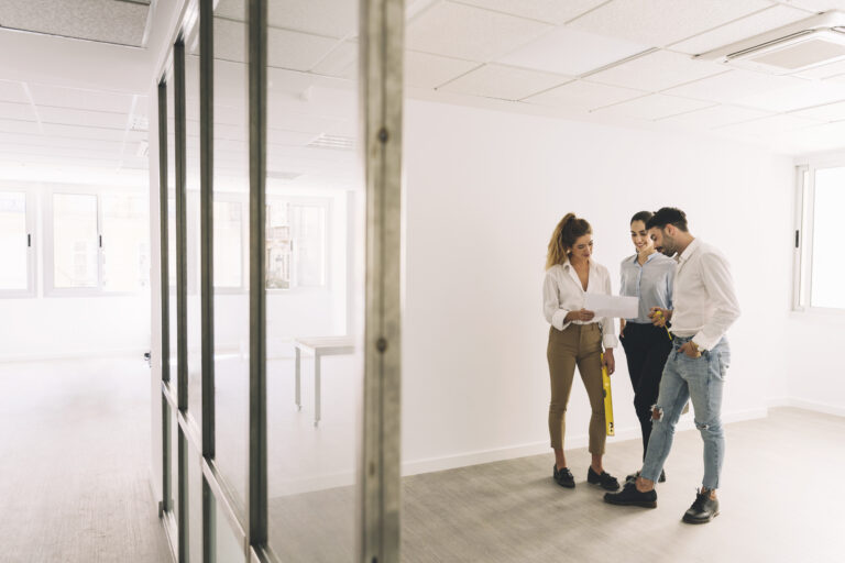 Equipo de profesionales revisando planos en un departamento vacío para inversión