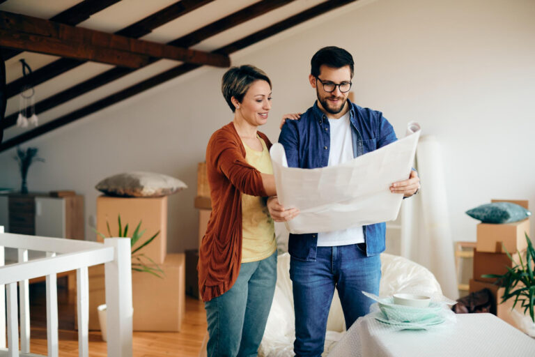 Pareja revisando planos de su nueva vivienda en medio de una mudanza