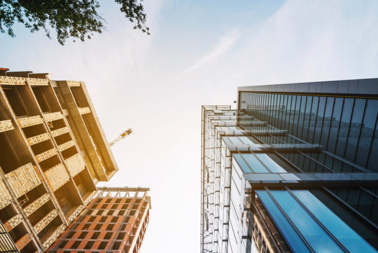 Vista ascendente de edificios en construcción y terminados, reflejando dinamismo inmobiliario
