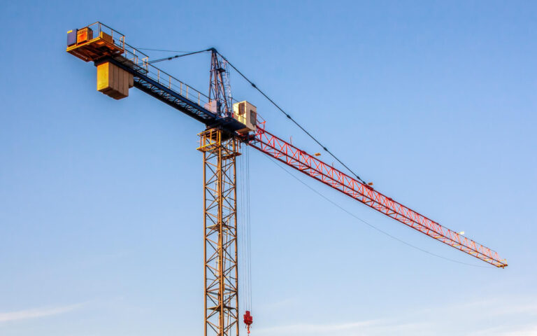 Grúa torre en faena de construcción bajo cielo despejado, representando la industria inmobiliaria en expansión