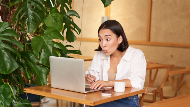 Mujer usando un notebook para buscar propiedades online con ilustraciones de casas y documentos