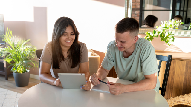 Pareja revisando información desde una tablet con ilustraciones de asistencia y acompañamiento digital